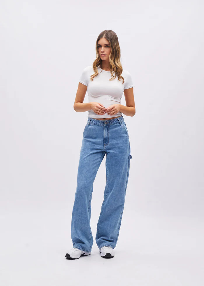 Woman wearing a white t-shirt and blue jeans on a white background