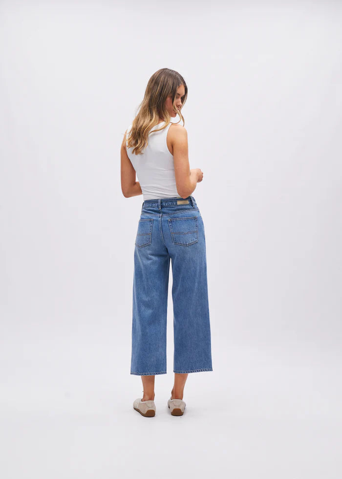 Woman wearing blue jeans and a white top on a white background
