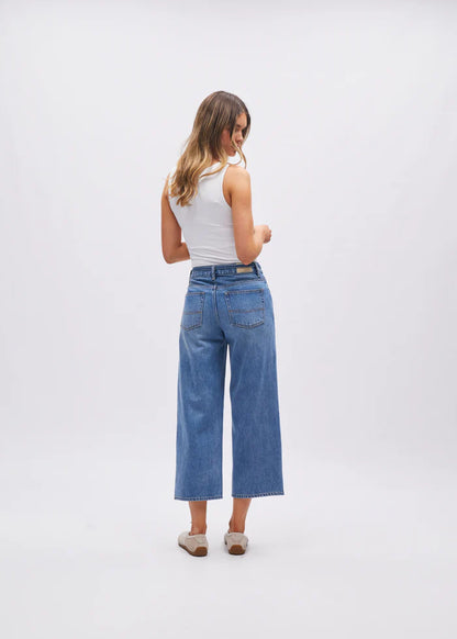 Woman wearing blue jeans and a white top on a white background
