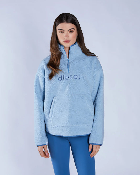 Woman wearing a light blue 'Diesel' sweatshirt against a white background