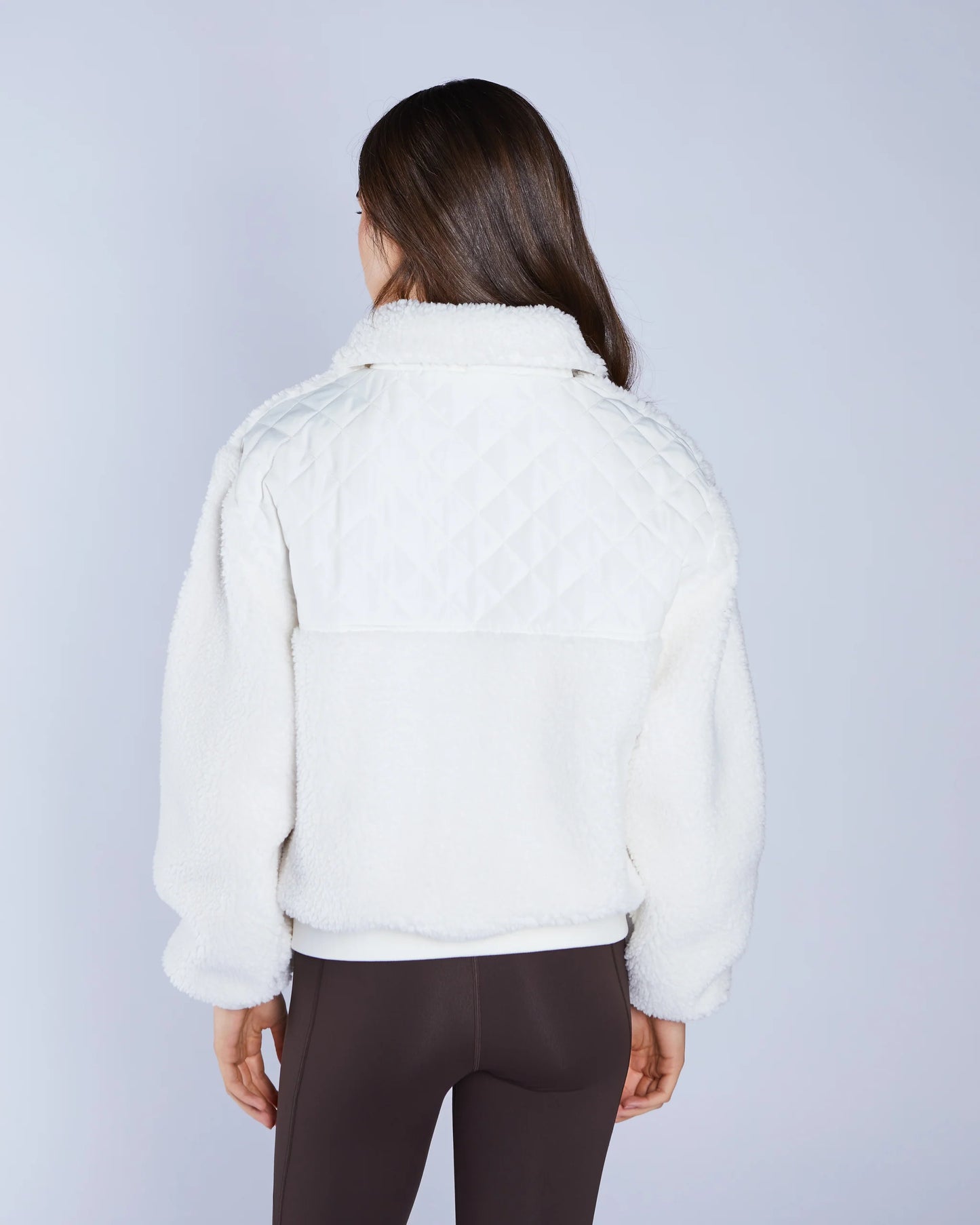 Person wearing a white jacket on a plain background