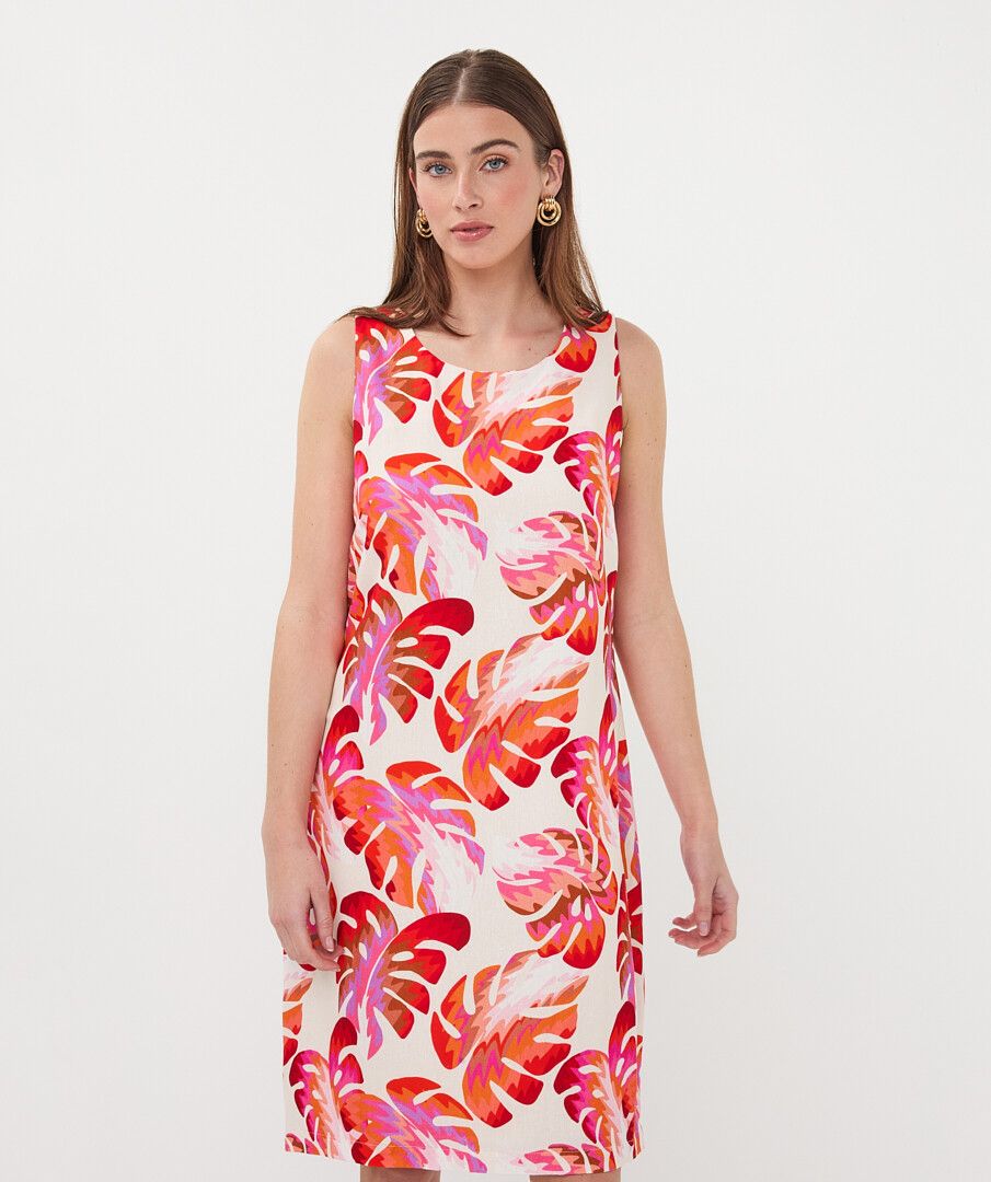 Woman wearing a sleeveless dress with colorful leaf pattern on a white background