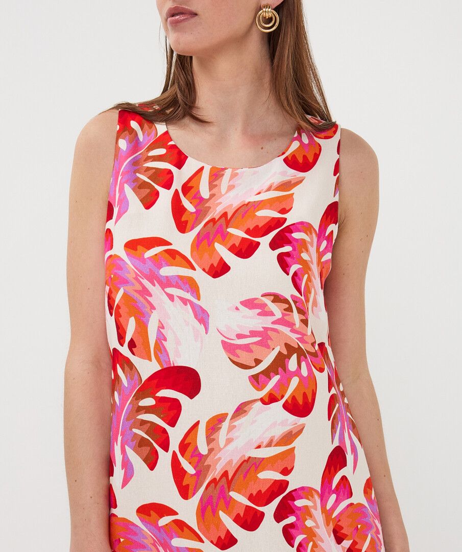Woman wearing a sleeveless dress with a colorful floral pattern on a plain background