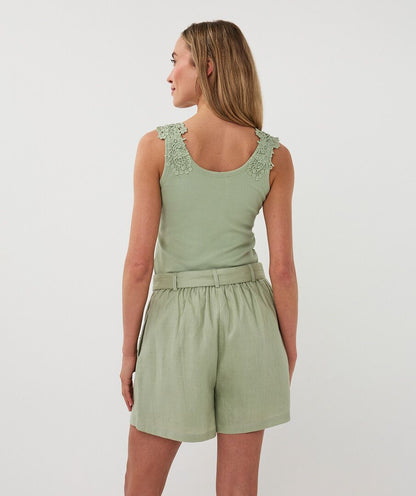 Woman wearing a green sleeveless top and shorts set on a white background
