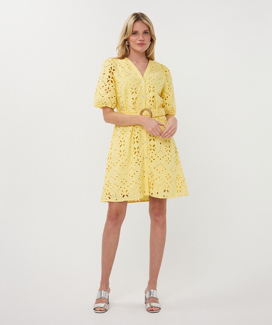 Woman wearing a yellow dress with cut-out details on a white background