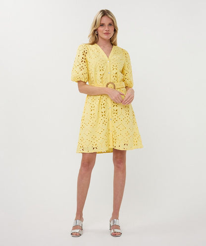 Woman wearing a yellow dress with cut-out details on a white background