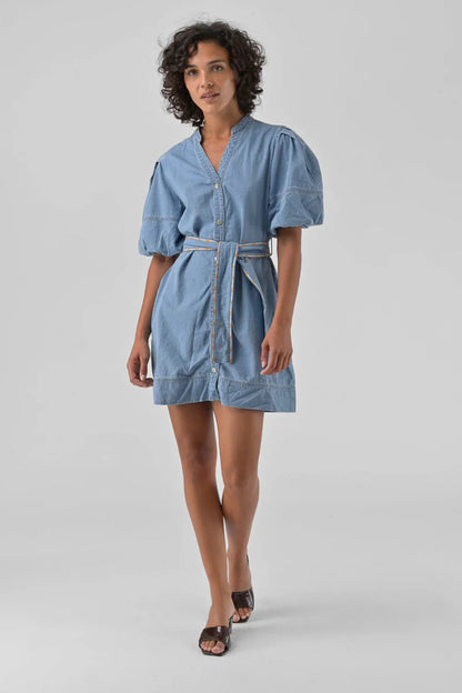 Woman wearing a blue denim dress on a gray background