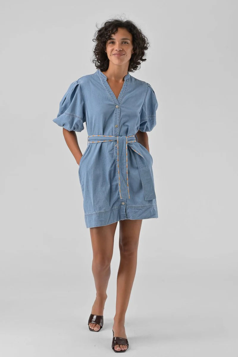 Woman wearing a blue dress with a belt on a gray background