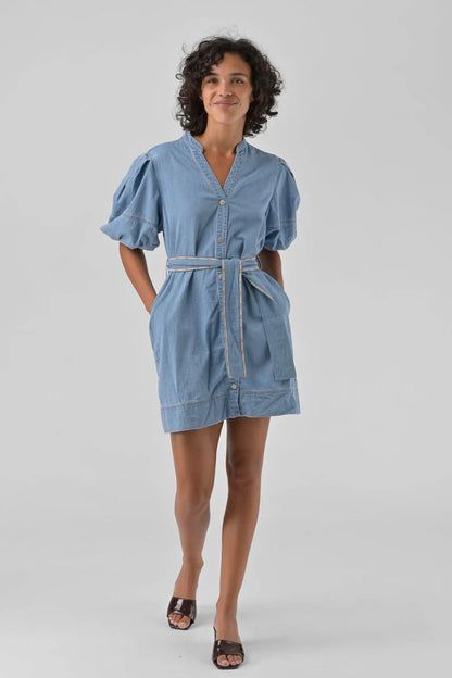 Woman wearing a blue dress with a belt on a gray background