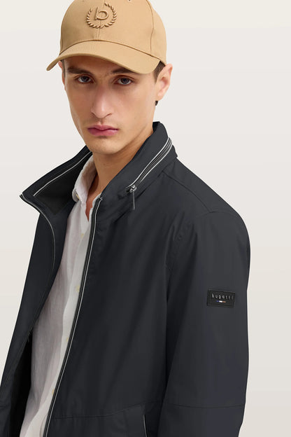 Man wearing a black jacket and beige cap on a light background