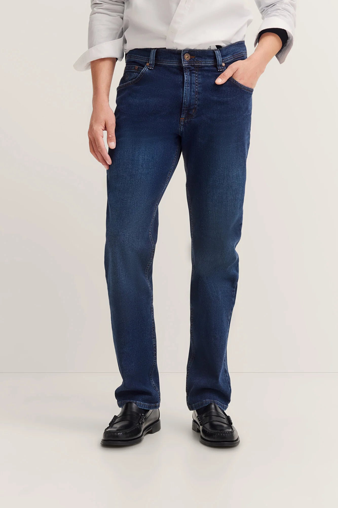 Person wearing dark blue jeans on a white background
