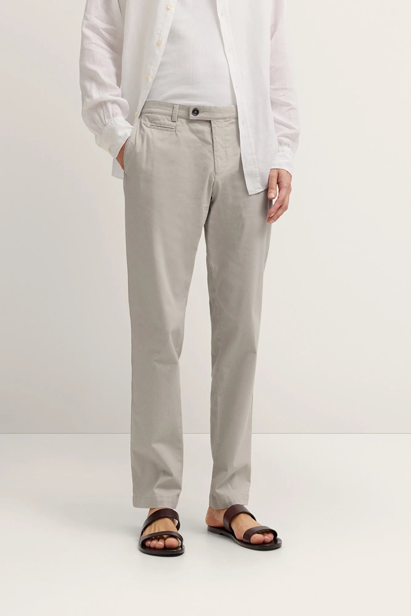 Person wearing light gray pants and a white shirt on a white background
