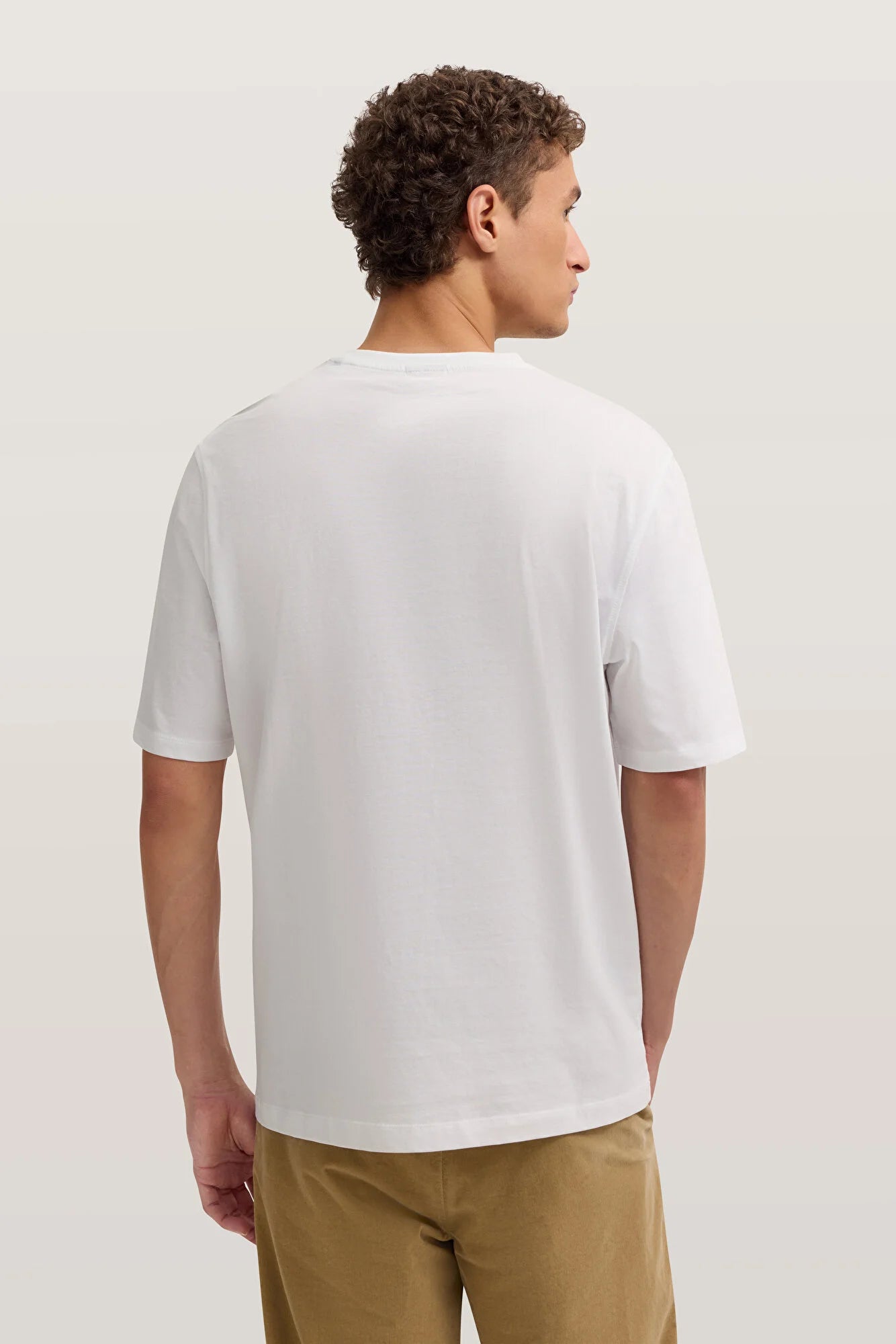 Person wearing a plain white t-shirt on a light background