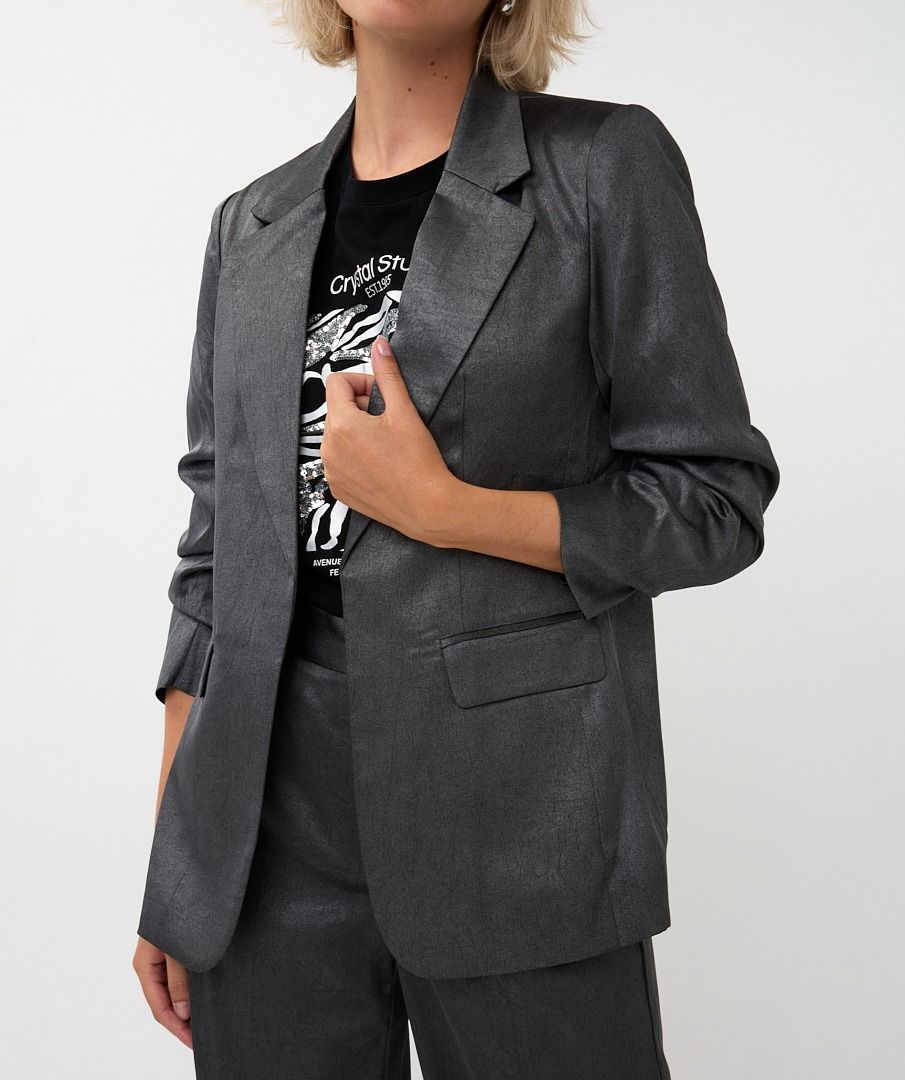 Person wearing a gray blazer over a black graphic t-shirt on a white background